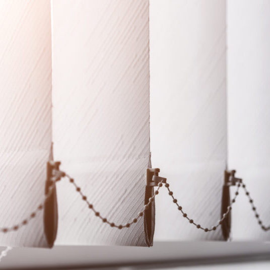 Texture of white paper venetian roller blind hanging on office window closeup