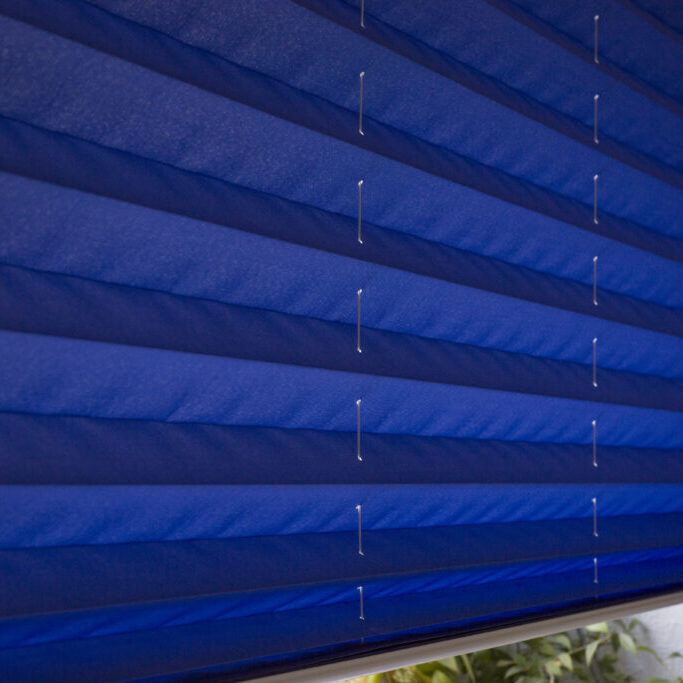 Pleated blinds XL, blue color, with 50mm fold closeup in the details on the window in the interior. Home blinds - modern bottom up privacy shades on apartment windows.