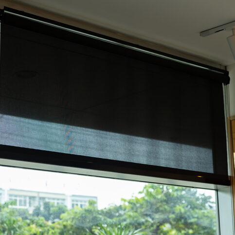 A window with a black curtain that is drawn. The curtain is drawn all the way to the bottom of the window