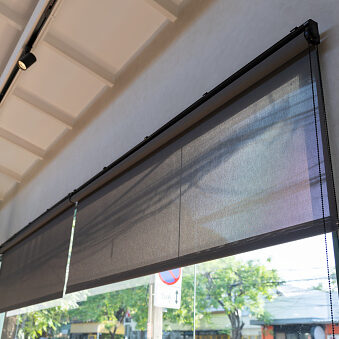 A window with a black screen that is open to the outside. black rolling blind curtain with window shop.